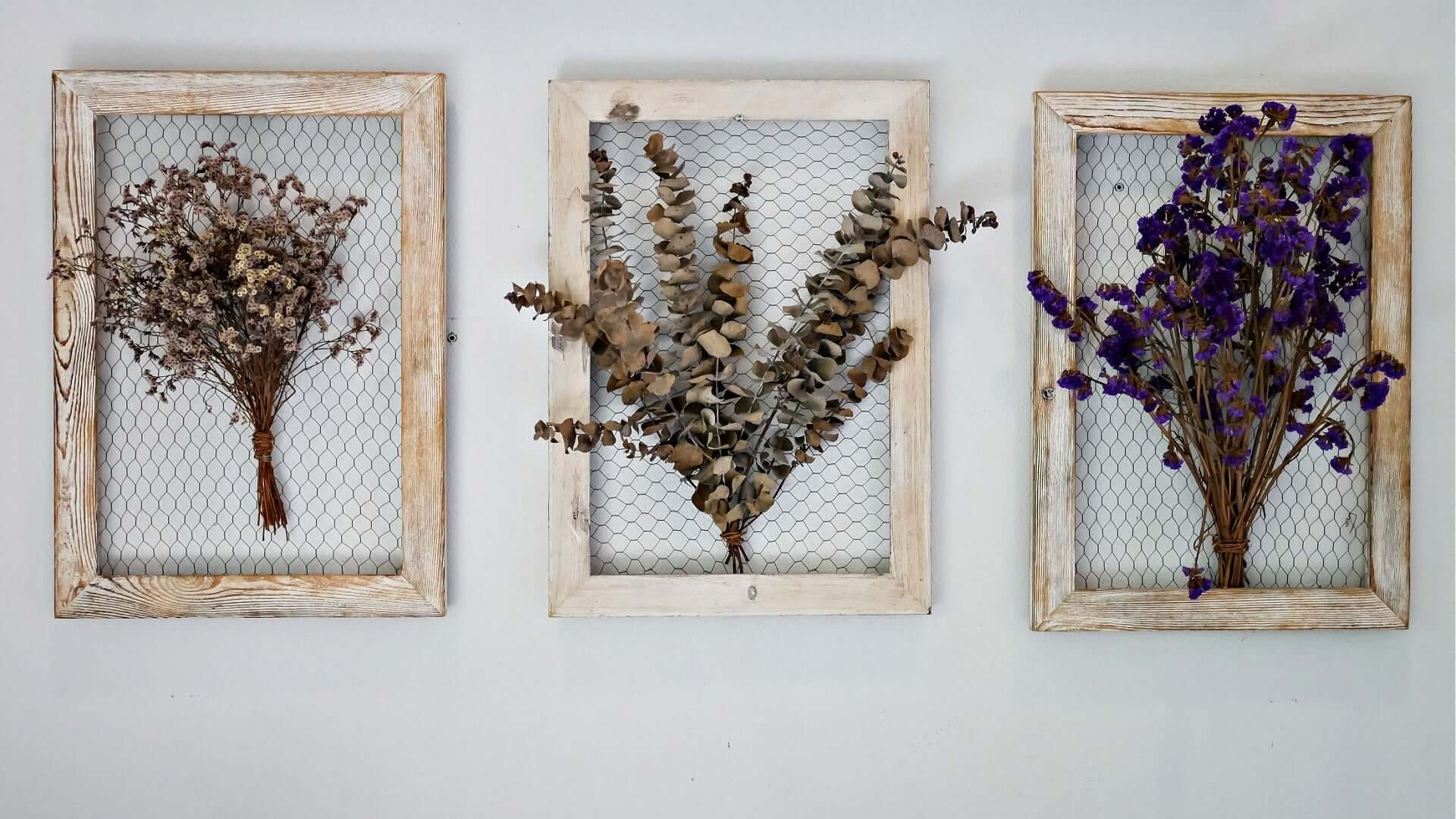 Three rustic wooden-framed dried floral wall art pieces with wire mesh