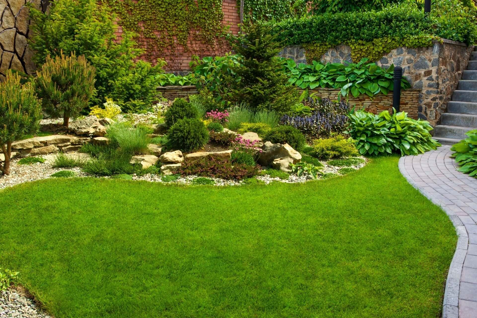 Lush green lawn with curved stone path amid shrubs and flowers for landscaping