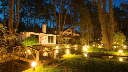 Warmly lit rustic wooden bridge over tranquil pond in outdoor space
