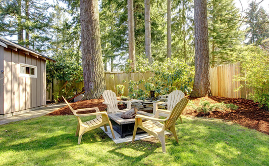 Light beige Adirondack chairs around stone fire pit in sunny backyard