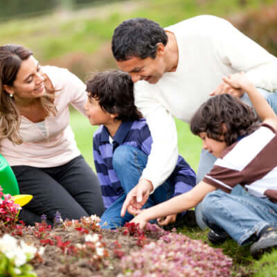 Family gardening with children around colorful flower bed