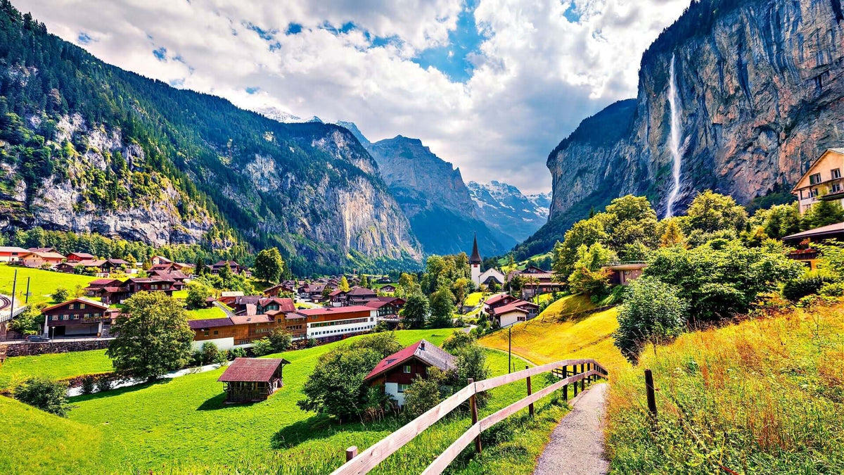 Captivating landscape of village in lush valley with waterfall and mountains