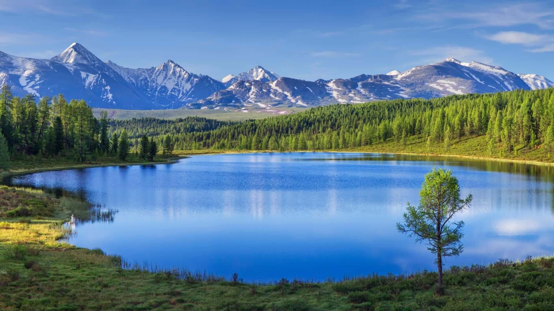 Serene deep blue lake mirroring snow-capped mountains vital to plant growth