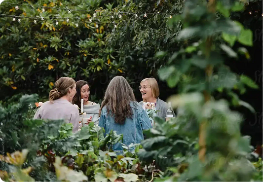 Women gardeners chatting in garden under string lights