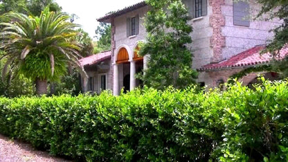 Stucco brick Mediterranean house with red tile roof and Wax Leaf Privet greenery